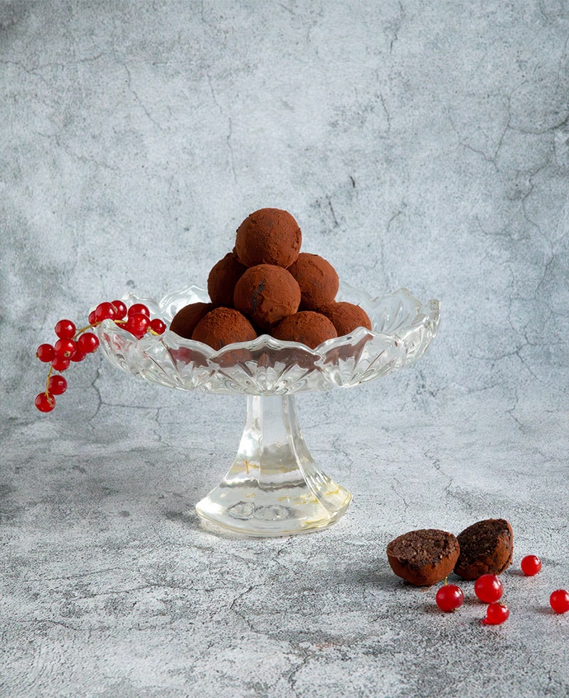 Mandelmehl-Trüffel mit Kakao in einer Glasschale angerichtet, dekoriert mit roten Beeren