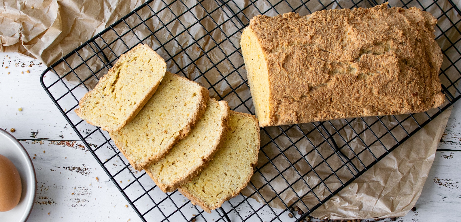 4 Mandelmehlbrotscheiben auf einem schwarzen Abkühlgitter von oben.