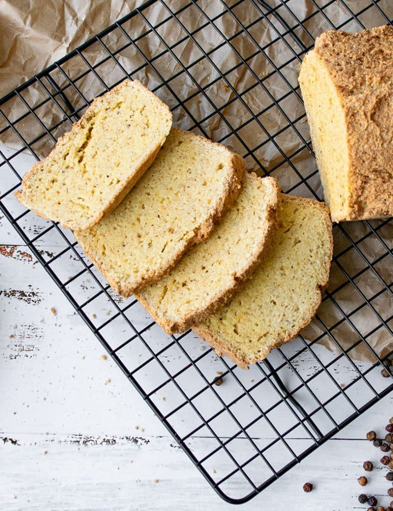 4 Scheiben Mandelmehlbrot auf einem schwarzen Abkühlgitter von oben fotografiert. 