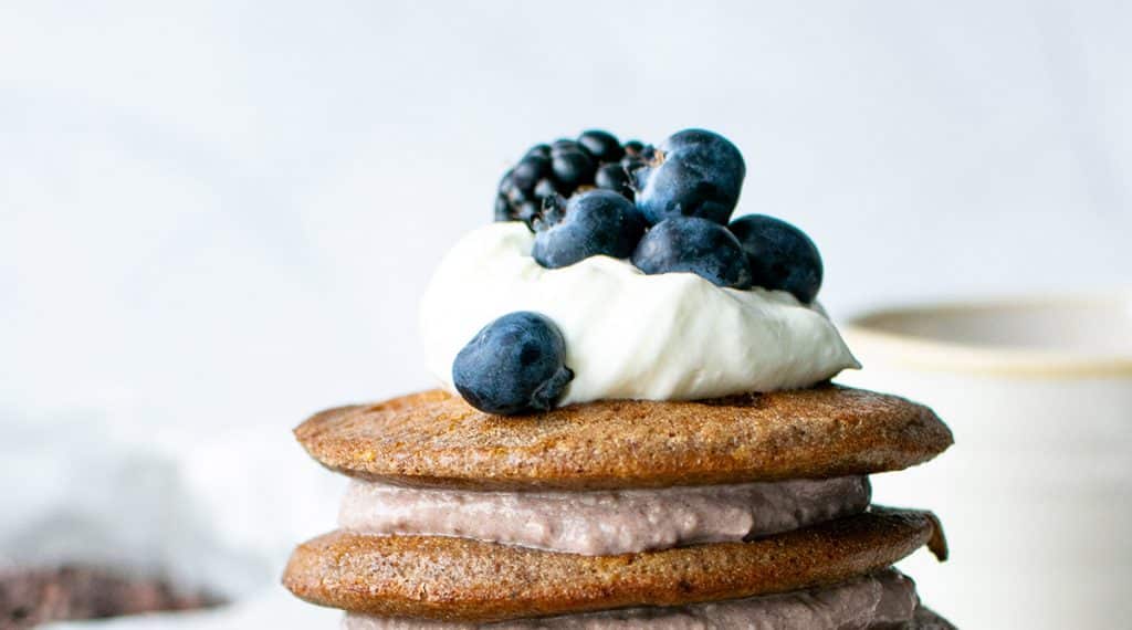 Mandelmehl-Pancakes - der obere Teil des Turms von vorn fotografiert. Die Creme wechselt sich ab mit den Pancakes, obendrauf etwas Sahne-Mascarpone Creme und ein paar blaue Beeren. 