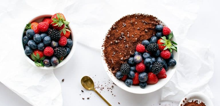 Low Carb Tiramisu Bowl mit Beeren und separate Schale frischer Beeren aus der Vogelperspektive.