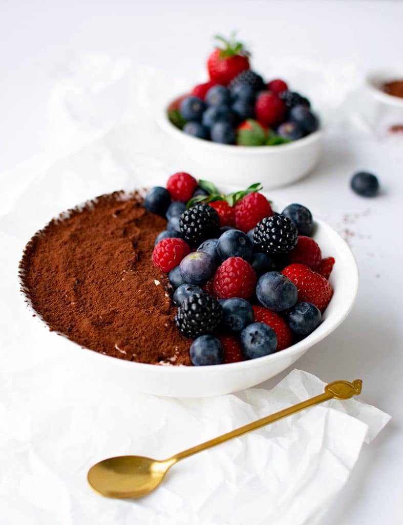Schüssel mit Mandelmehl-Tiramisu und Beeren im Vordergrund. Im Hintergrund eine kleine weiße Schüssel nur mit Beeren. 