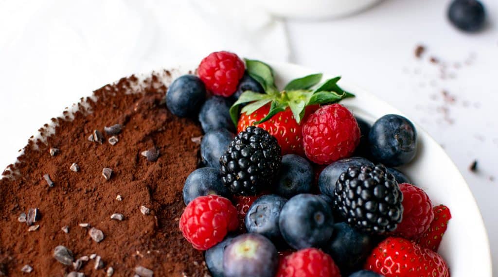 Close-Up: Cremiges Low Carb Tiramisu mit Kakao und Beeren in einer Schale