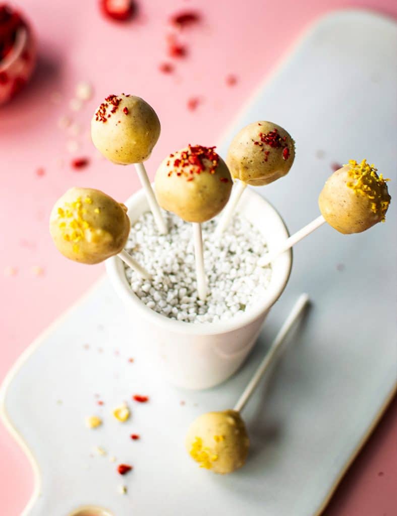 5 Lemen Cheesecake-Pops in einem Becher. Aufnahme von oben. Ein weiteret Pop liegt auf einem Tablett.