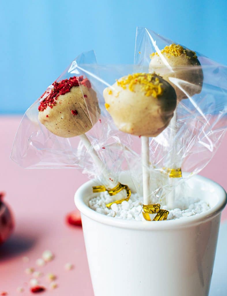 Drei Lemon Cheesecake-Pops verpackt in durchsichtigen Tüten in einem Becher
