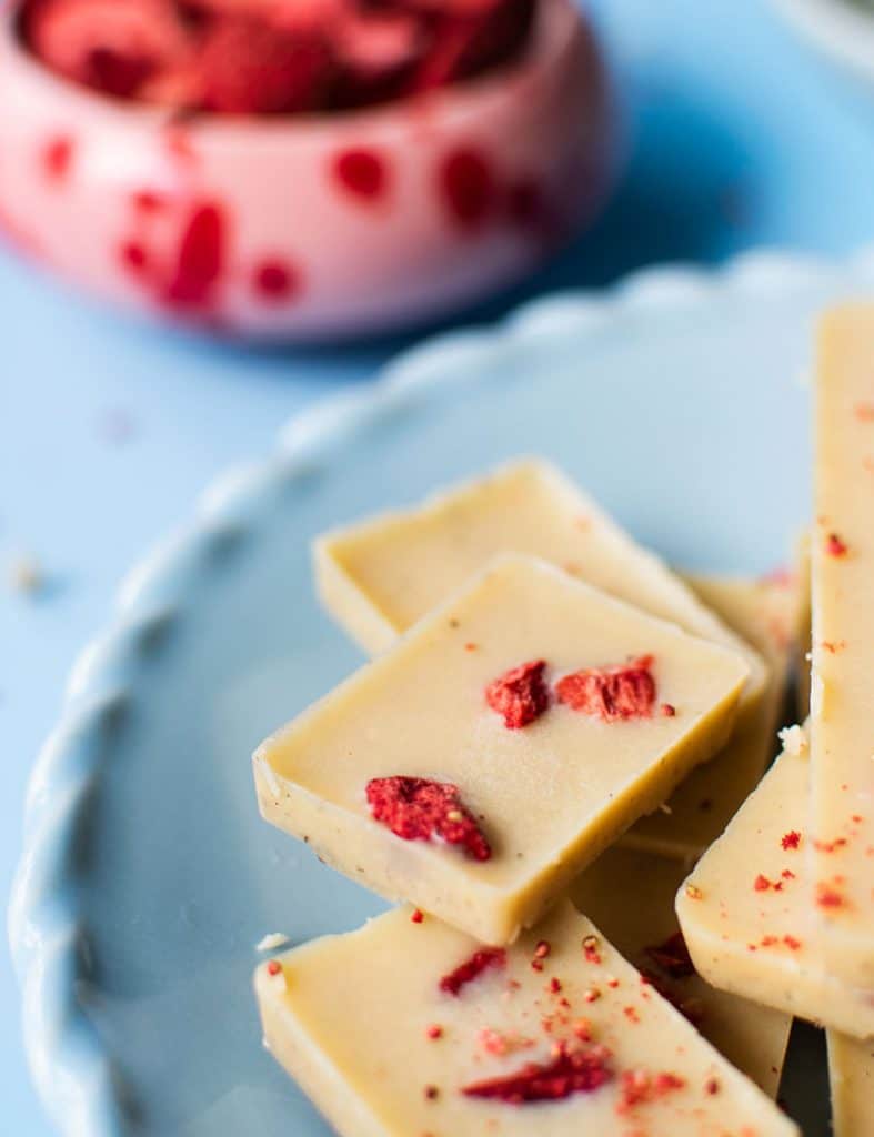 Weiße Schokolade mit ein paar Stückchen gefriergetrockneten Erdbeeren. Im Hintergrund eine Boogy Splash Dipschale von Butlers in rot